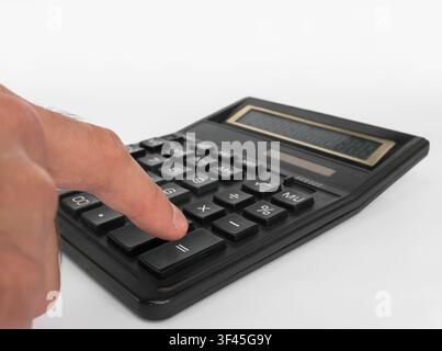 Human hand using a black office calculator to perform financial calculations. Close-up shot of a finger pressing the button Stock Photo