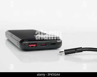 Black portable power bank with USB-C cable isolated on white background with reflection, external battery charger for smartphone Stock Photo