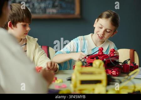 School kids assembling robotics project during classroom STEM lesson, developing teamwork and engineering skills. Ideal for education marketing, coding courses, innovation programs Stock Photo