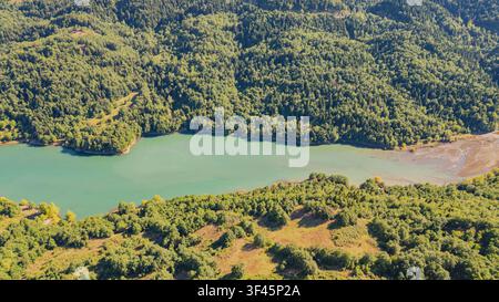Aerial panorama of emerald water inlet bounded by thick pine forest and rolling hills around Lake Plastiras in Greece for environmental nature travel Stock Photo