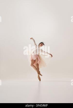 Graceful young brunette ballerina balancing en pointe in pink tutu viewed from behind Stock Photo