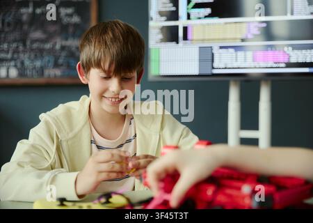 Caucasian schoolboy assembling robotics project in coding classroom, learning STEM skills through hands on teamwork. Ideal for education technology, coding camp, innovation marketing Stock Photo