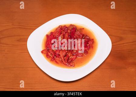 Roasted red pepper strips marinated in olive oil, plated on white square dish Stock Photo