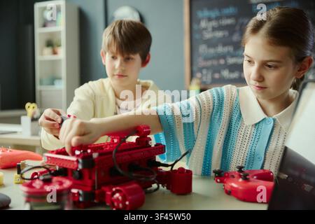 School kids assembling robotics project in classroom, learning engineering, coding, teamwork through hands on STEM activity. Ideal for education marketing, STEM programs, edtech promotion Stock Photo