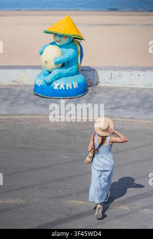 Young woman walking past a colorful turtle mascot statue, Nhon Hai, Gia Lai, Vietnam Stock Photo