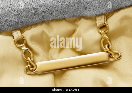 Blank golden clothes nameplate hanging on chains over fabric background closeup Stock Photo