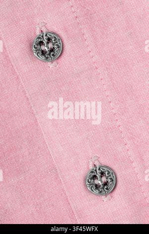 Two small elegant siler buttons on pastel pink cotton shirt closeup Stock Photo