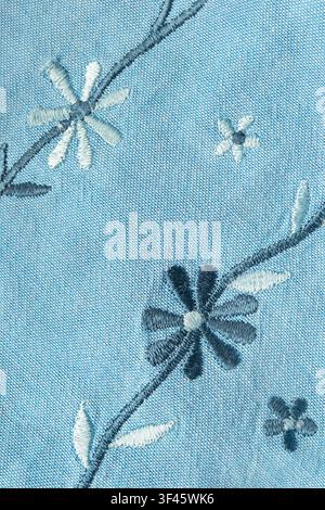Floral silk embroidery on light blue cotton fabric closeup as a background Stock Photo