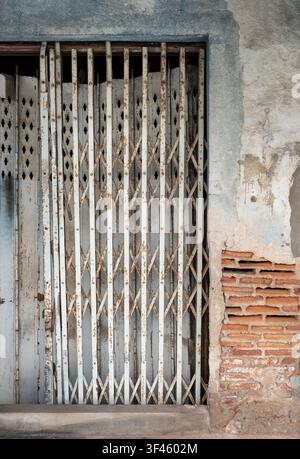 Samut Sakhon, Thailand - 03 Jun, 2026 - A captivating architectural detail featuring a classic, weathered folding metal shutter door set against an ag Stock Photo