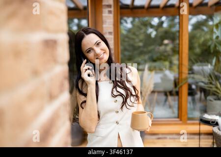 Smiling woman having phone conversation outdoors. Stock Photo