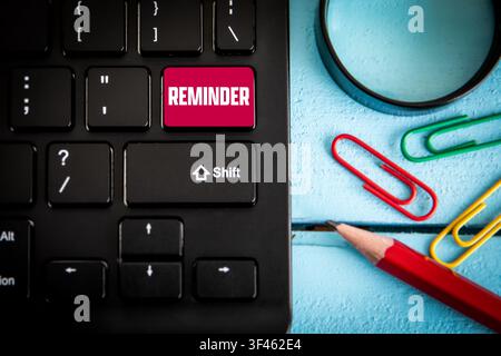 REMINDER word highlighted on keyboard key with magnifier and stationery on desk Stock Photo