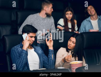 Young man talking on smartphone during film premiere in movie theater Stock Photo