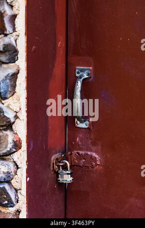 Metal door handle and padlock on closed wooden door. Stock Photo