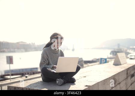 Happy woman works remotely on laptop outdoors Stock Photo
