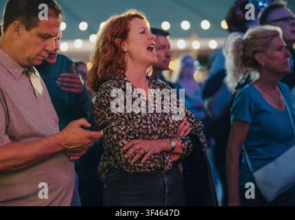 Woman sings along enthusiastically at outdoor concert Stock Photo