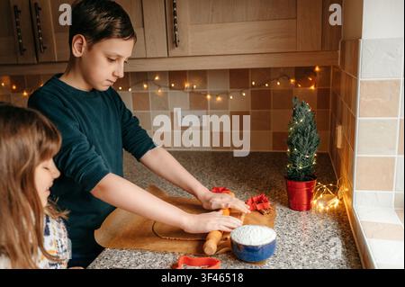 Siblings preparing Christmas cookies together in home kitchen Stock Photo