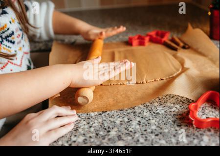 Close up of child rolling Christmas cookie dough on baking paper Stock Photo