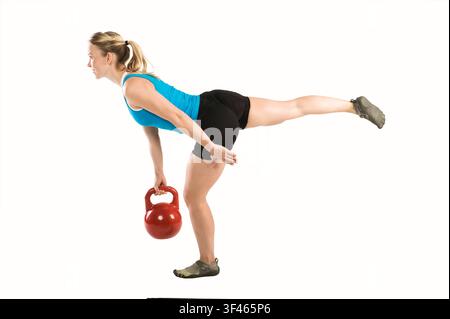 Woman performing single leg kettlebell good morning balance exercise Stock Photo
