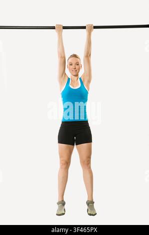 Woman hanging from pull up bar smiling Stock Photo
