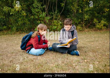 Brother and sister reading together outdoors before school Stock Photo