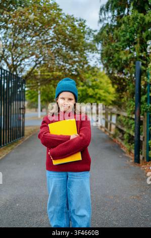 Girl holding school notebooks near the entrance to a school Stock Photo