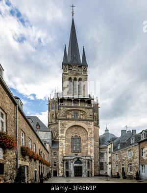 Aachen Cathedral (Aachener Dom) low angle view framed by historic brick buildings under a cloudy sky in Aachen, Germany. Stock Photo