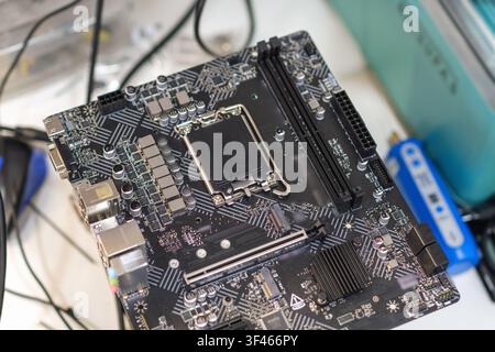Close-up view of a computer motherboard with various components and circuitry, showcasing intricate details and connections in a tech workspace Stock Photo