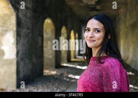 Beautiful young woman smiling in a long stone hallway Stock Photo