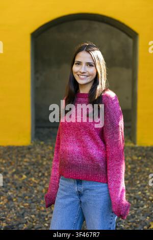 Happy young woman in a pink sweater smiling outdoors Stock Photo
