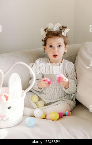 Surprised toddler discovers toys inside Easter eggs at home Stock Photo