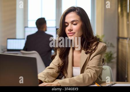Focused young businesswoman working on laptop at office desk, startup manager Stock Photo