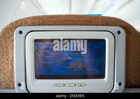 In-flight entertainment screen displaying world map and flight route inside airplane cabin. Stock Photo