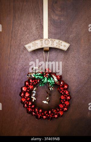 Festive red jingle bell wreath with joy sign on a door Stock Photo