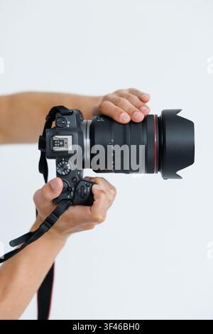 Closeup of photographer pointing DSLR camera at screen on white background. Stock Photo