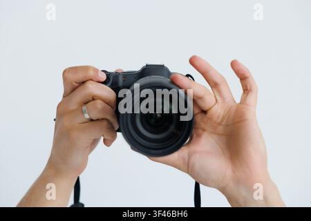 Closeup of photographer pointing DSLR camera at screen on white background. Stock Photo