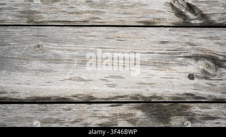 A high-angle, close-up shot of weathered wooden planks arranged horizontally. The wood features a prominent natural grain, several knots, and a faded Stock Photo