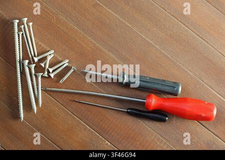 Screwdrivers and metal screws arranged on wooden surface with copy space Stock Photo