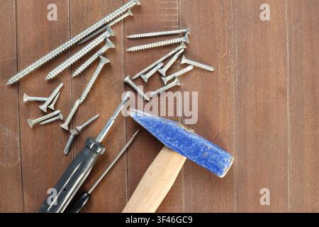 Hammer screwdrivers and metal screws arranged on wooden surface with copy space Stock Photo