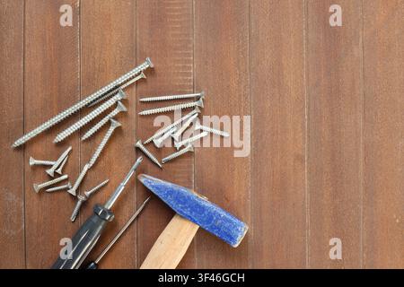 Hammer screwdrivers and metal screws arranged on wooden surface with copy space Stock Photo