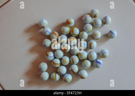Colorful Glass Marbles on White Tile Floor with Dramatic Sunlight and Shadows, Vintage Childhood Game Concept, Minimal Still Life Background with Copy Stock Photo