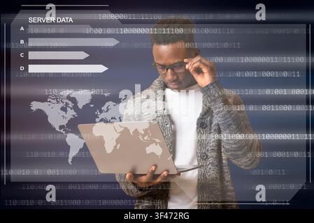 Black hacker holding laptop looking at database server Stock Photo