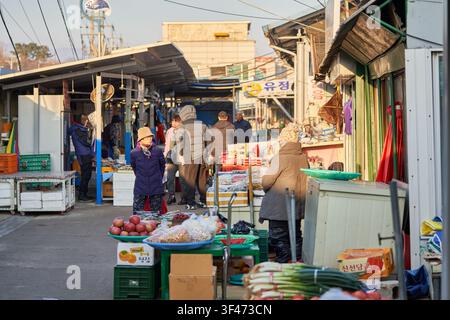Traditional morning market back alley in winter with a merchant and fresh produce under sunlight. Stock Photo