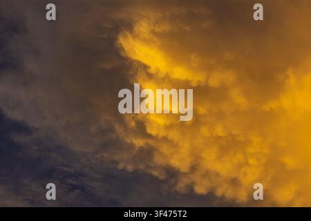 A gold cloud sky sunset dramatic cloudscape with textured mammatus formation and deep blue contrast evoking awe and calm Stock Photo