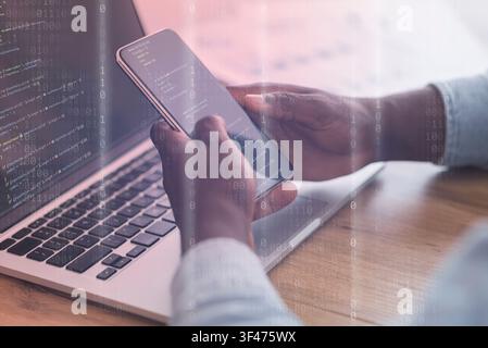 Mobile Security Concept. Black man using phone and laptop Stock Photo