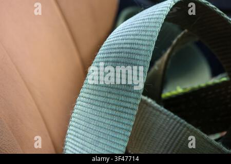 A light green woven nylon strap close up showing texture and frayed fibers with soft leather seat background conveying tactile detail and calm mood Stock Photo