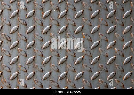 A rusty metal diamond plate texture with raised tread pattern and weathered surface conveying industrial grit and aged character Stock Photo