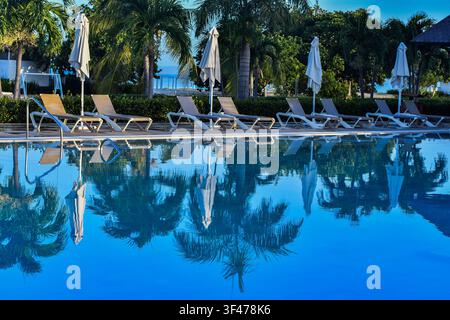 Trinidad, Cuba - July 2026: Sun loungers and palm tree reflections on the swimming pool at the Melia Trinidad Peninsula resort. Stock Photo