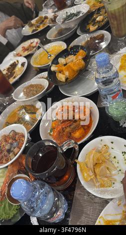 Overhead view of assorted Padang food served in small plates and bowls at an Indonesian restaurant, showcasing a variety of traditional Minangkabau di Stock Photo