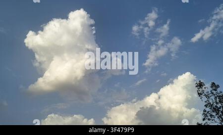 Fluffy white cumulus clouds floating in a bright blue sky on a sunny day Stock Photo