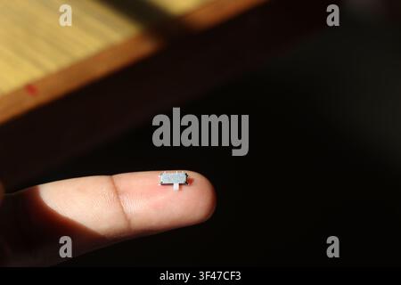 Micro SMD slide switch of horizontal type used in electronic circuits and printed circuit boards held in the tip of finger Stock Photo